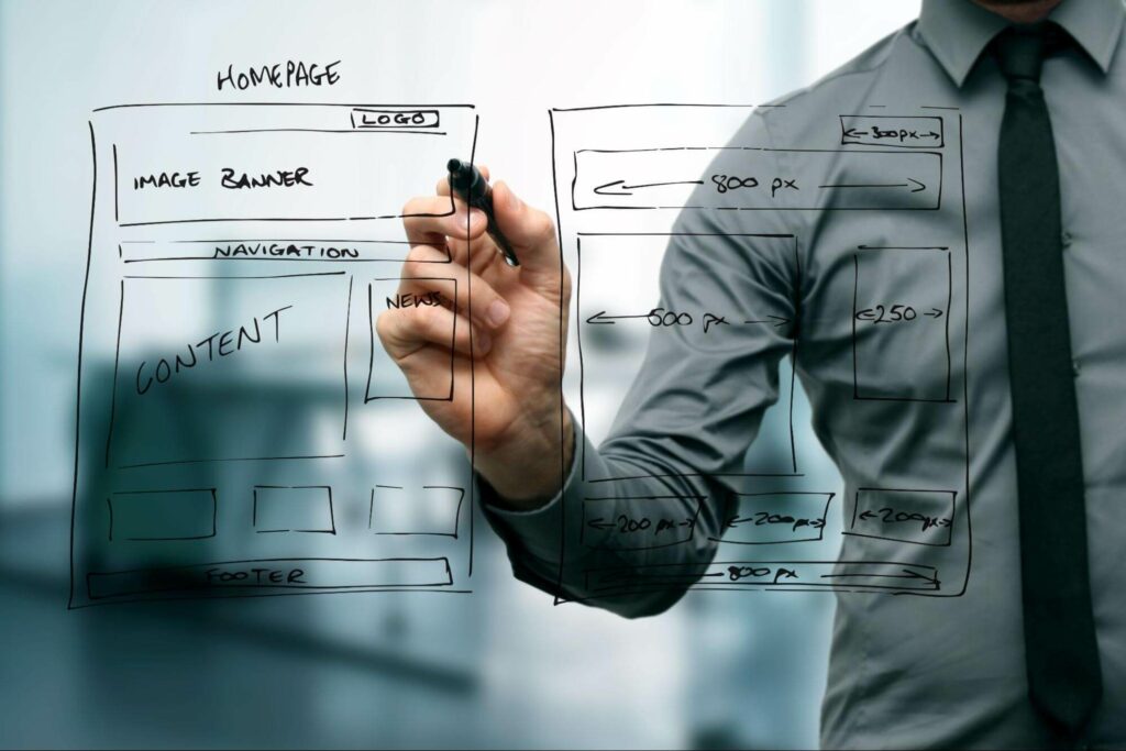 A man in a gray shirt and black tie writes on a clear surface facing the camera, outlining a website homepage layout with blocks for different elements relating to UX copywriting.