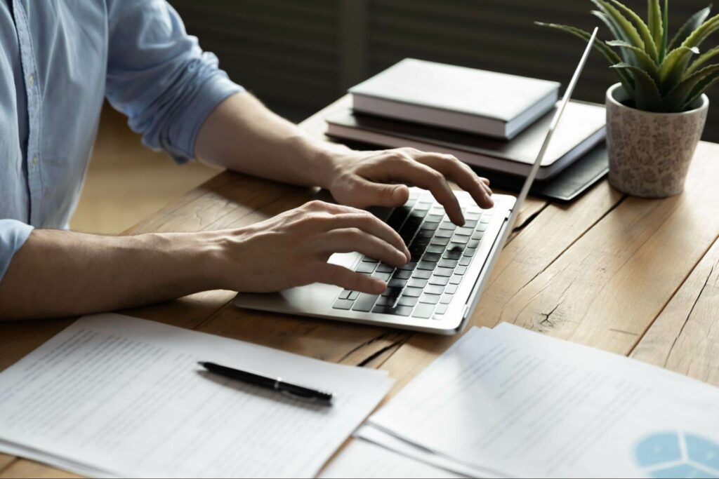 A man writes a blog for his business on a laptop.