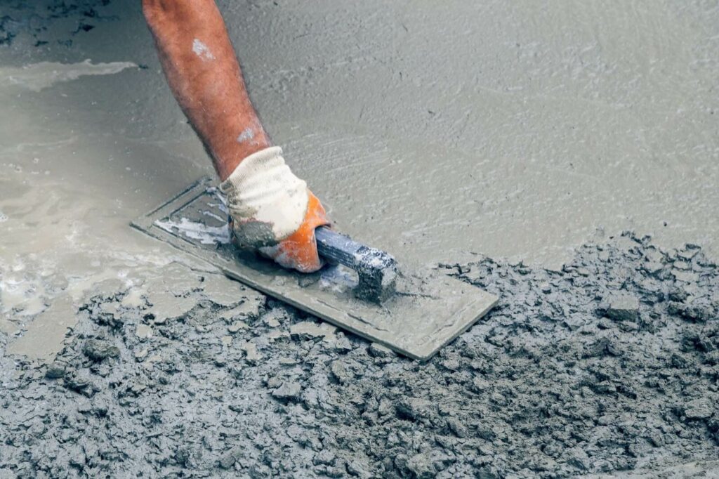 A contractor smooths concrete with a hand tool.